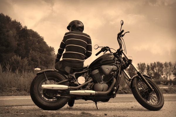 man op motor met helm op met bos als achtergrond