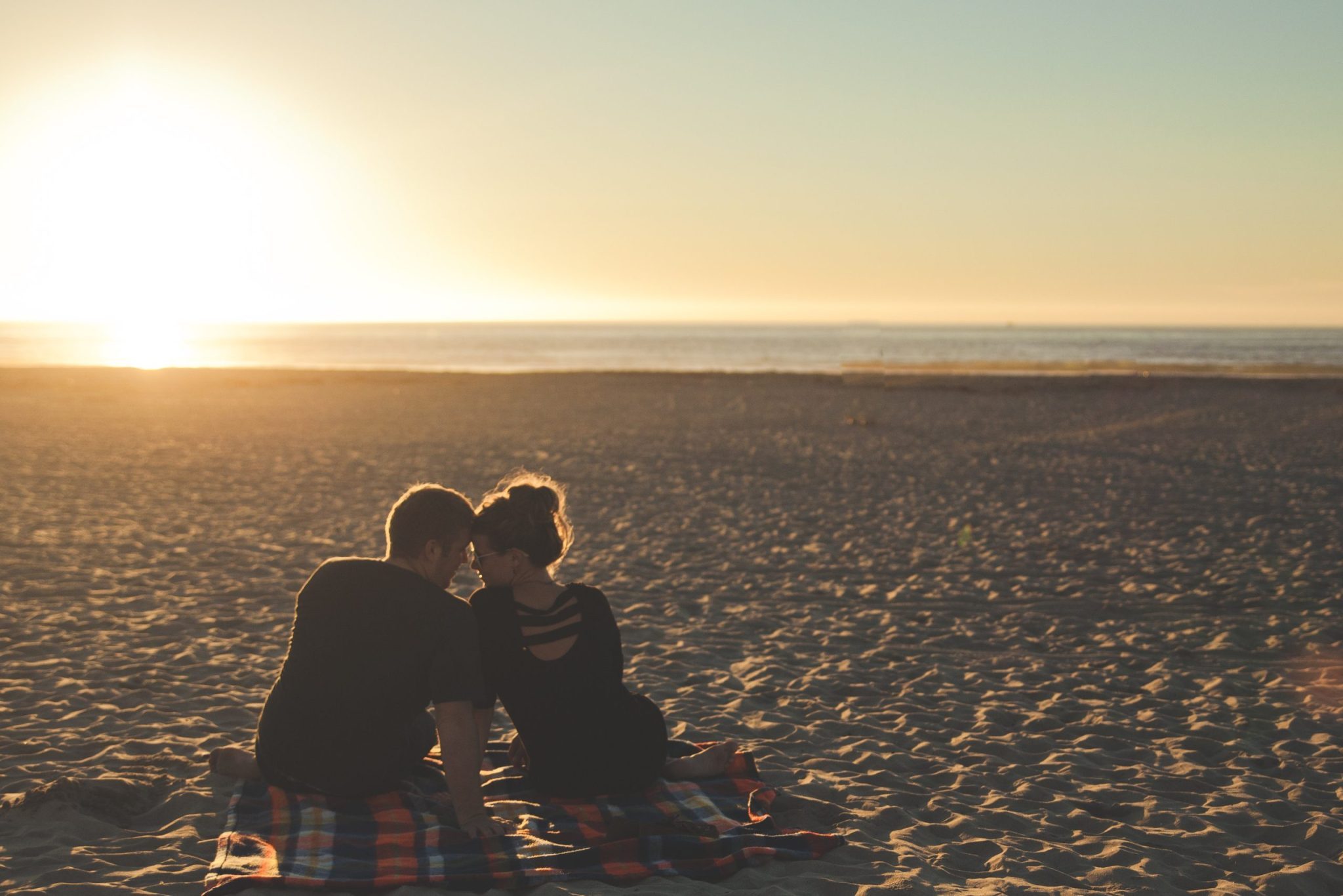 Twee mensen die romantisch op het strand zitten
