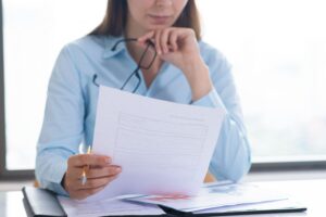 Vrouw bekijkt aandachtig een verzekeringsdocument aan haar bureau – zakelijke verzekeringen vergelijken
