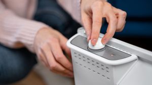 Persoon stelt een Helthome luchtontvochtiger in met een draaiknop op het apparaat